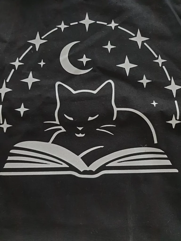 Tote bag noir avec design chat lisant un livre sous les étoiles — impression personnalisée sur mesure par MonTote.ch en Suisse